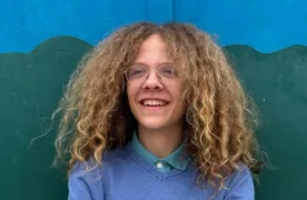 Uczeń na tle niebiesko-zielonej ściany.