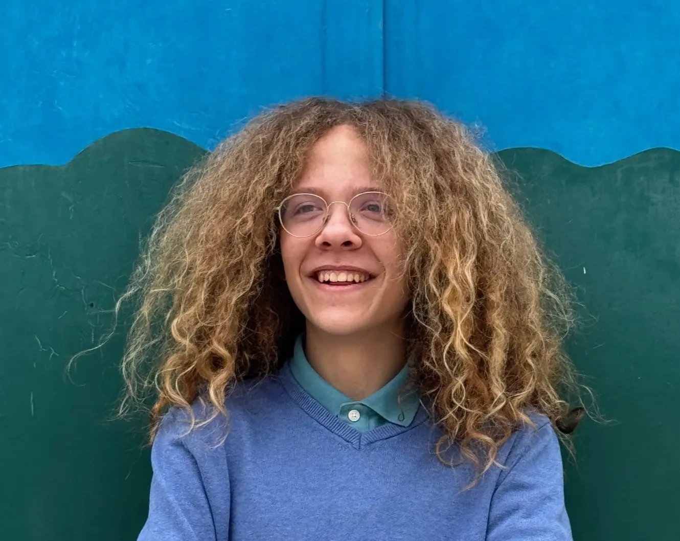 Uczeń na tle niebiesko-zielonej ściany.